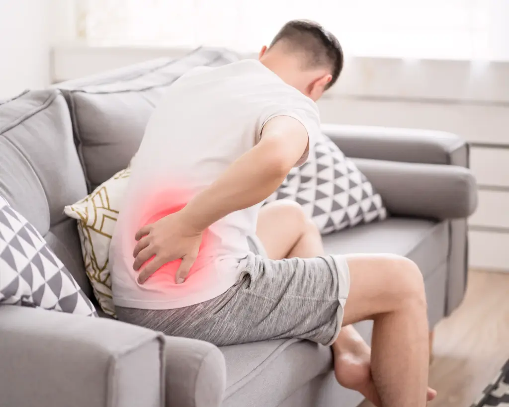 Homme souffrant de mal de dos sur canapé.