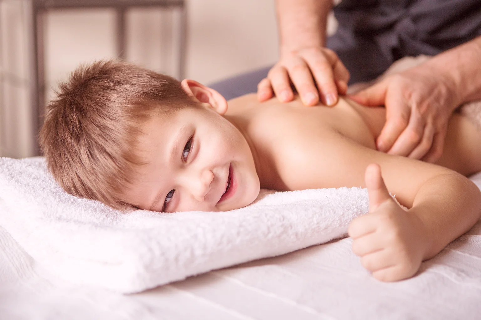 Enfant souriant recevant un soin, pouce levé.